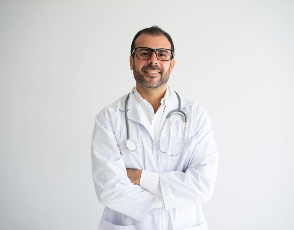 Portrait of successful mid adult doctor with crossed arms. Caucasian general practitioner wearing lab coat, glasses and stethoscope looking at camera and smiling. Medical worker concept